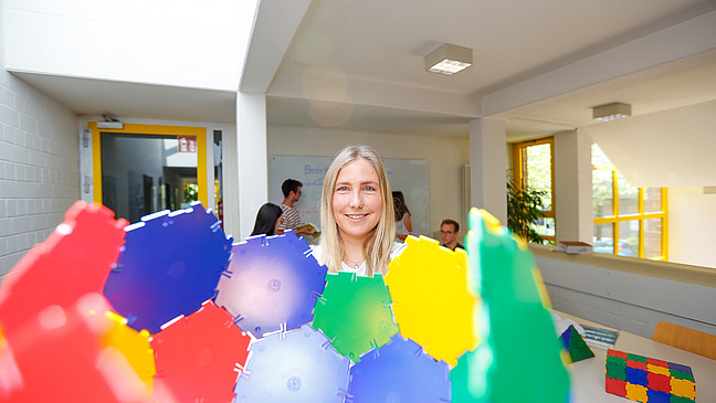 A student holds a structure made of colorful hexagons up to the camera