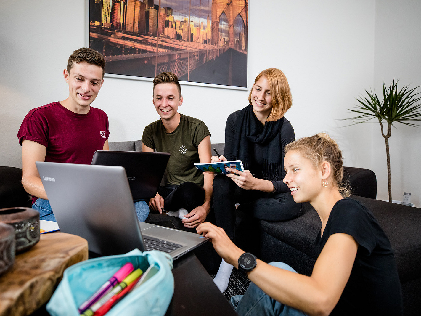 our young adults are gathered around a laptop. The group appears engaged and collaborative, discussing ideas and sharing notes. 