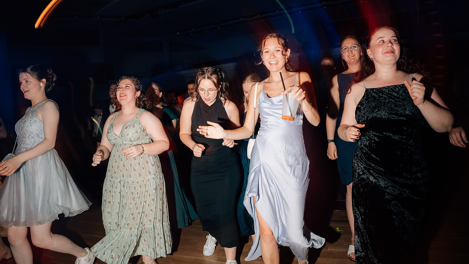 A group of people dance, one person smiles into the camera