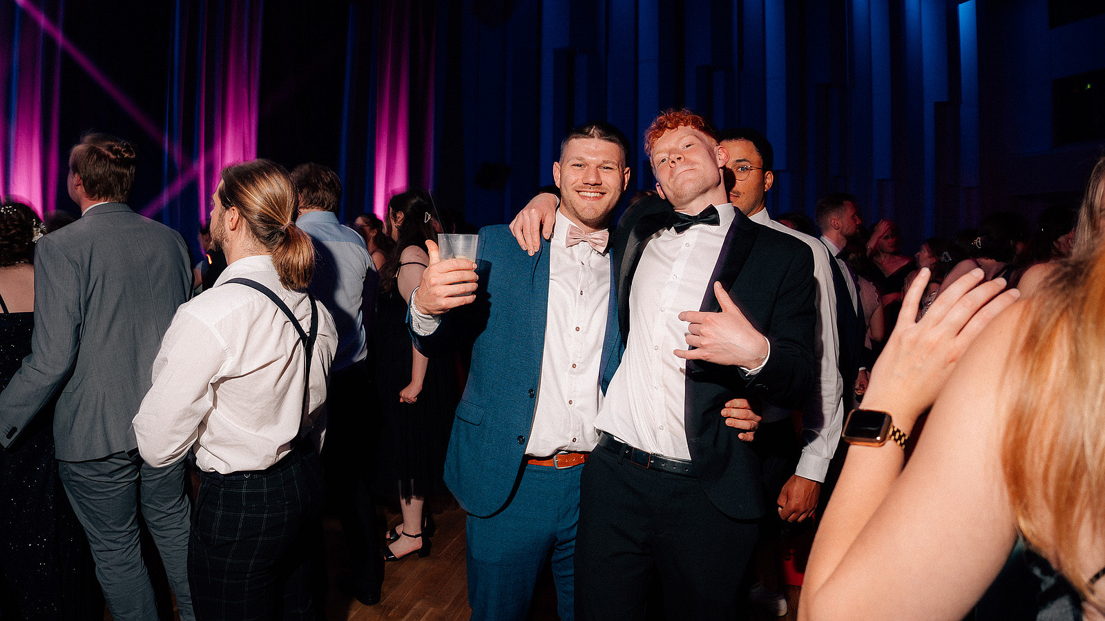 Two people arm in arm on the dance floor looking into the camera