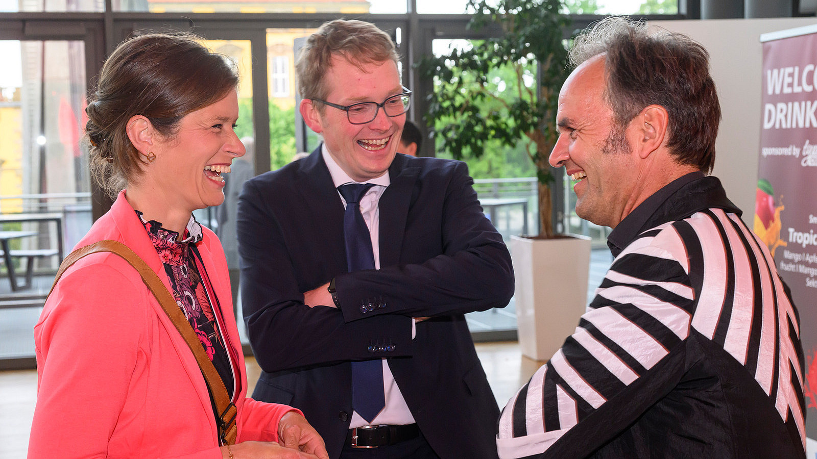 Three people stand together laughing