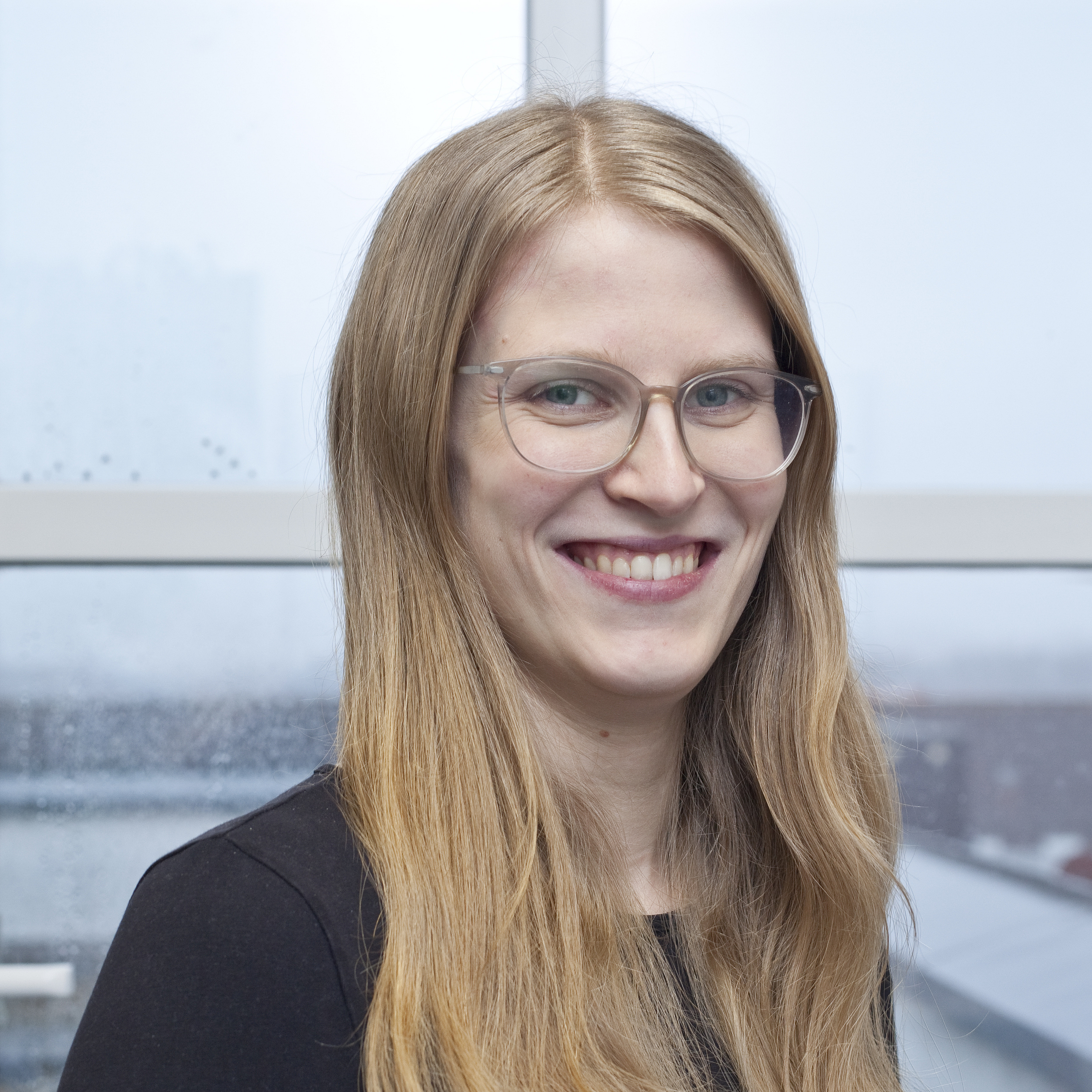 Portraitfoto von einer Frau mit langen, blonden Haaren und einer Brille