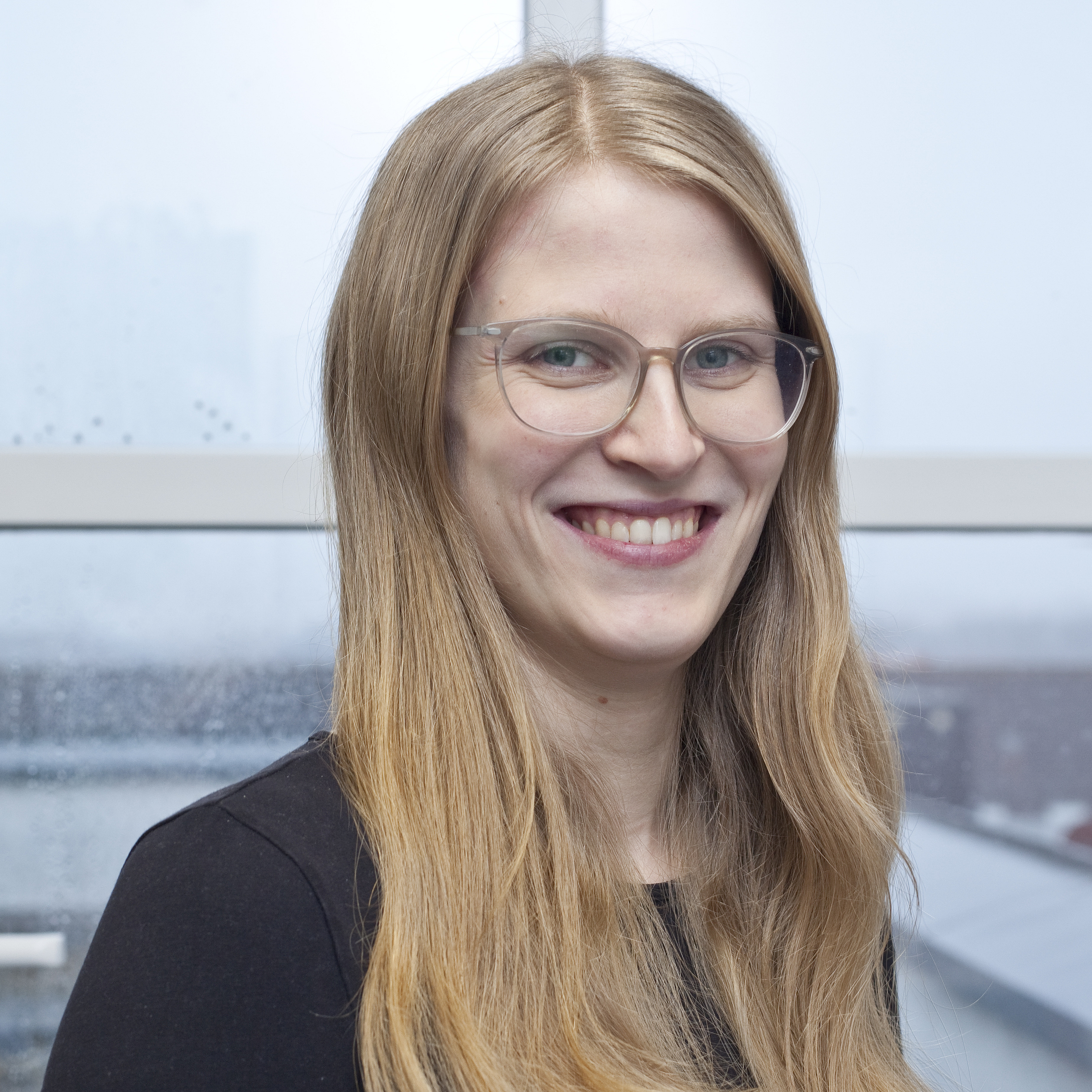 Portraitfoto von einer Frau mit langen, blonden Haaren und einer Brille