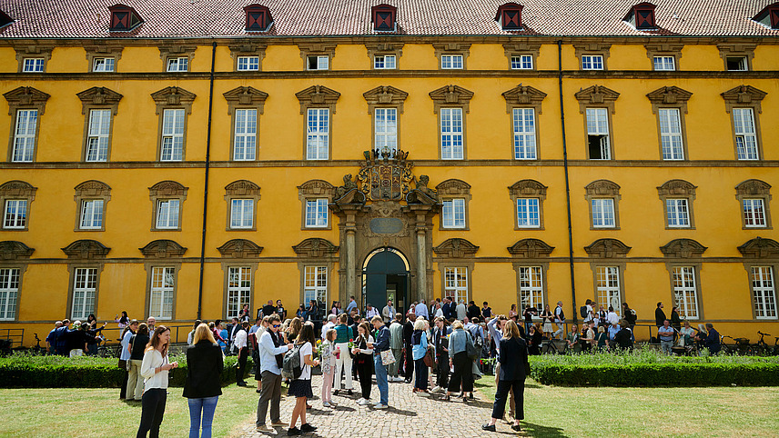 Zahlreiche Personen stehen vor einem historischen Gebäude.