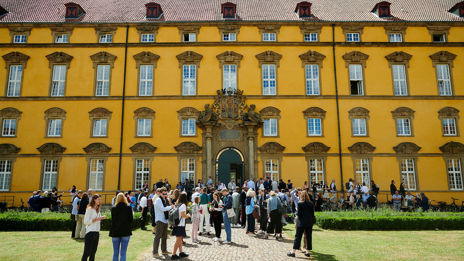 Zahlreiche Personen stehen vor einem historischen Gebäude.