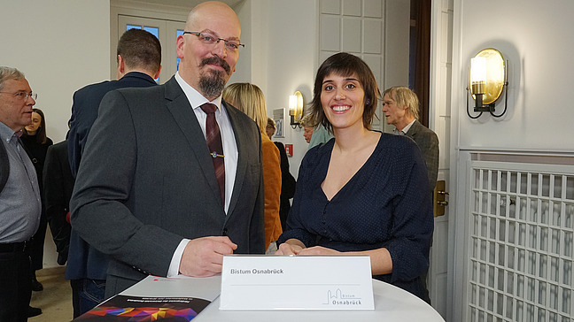 Ayla Ürkmez steht neben Jens Kuthe, der ihr die Förderurkunde des Bistums Osnabrück übergibt.