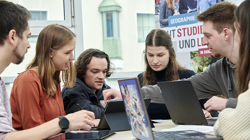 Eine Gruppe Studierender mit Laptops an einem Gruppentisch