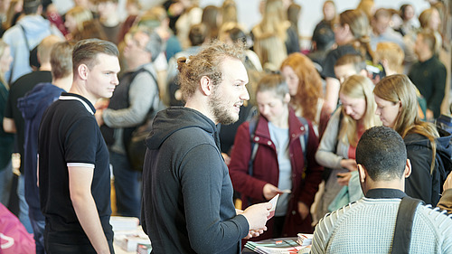 Numerous people in a hall and at information stands