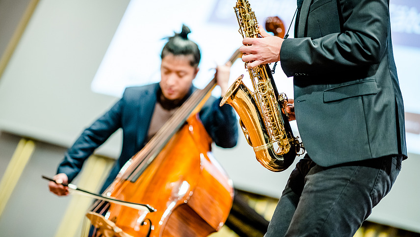 Zwei Personen machen Musik beim Wissensforum 2019. Mattis Balks spielt Saxophon und Minh Voong spielt Cello.