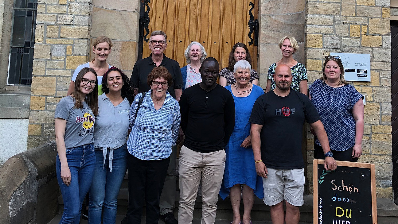Group photo of people standing in front of a stone building