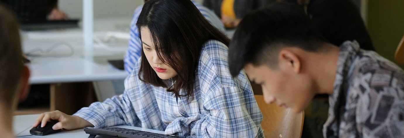 Chinesische Studierende sitzen an PC- Tastatur und PC-Maus