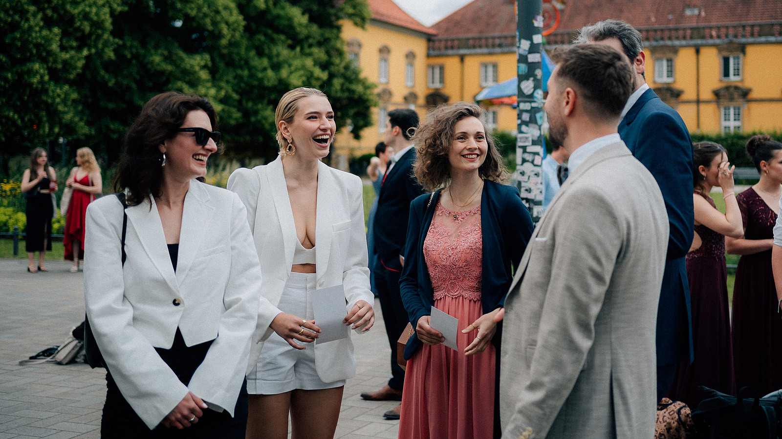 Several people stand in a good mood in front of the Osnabrückhalle