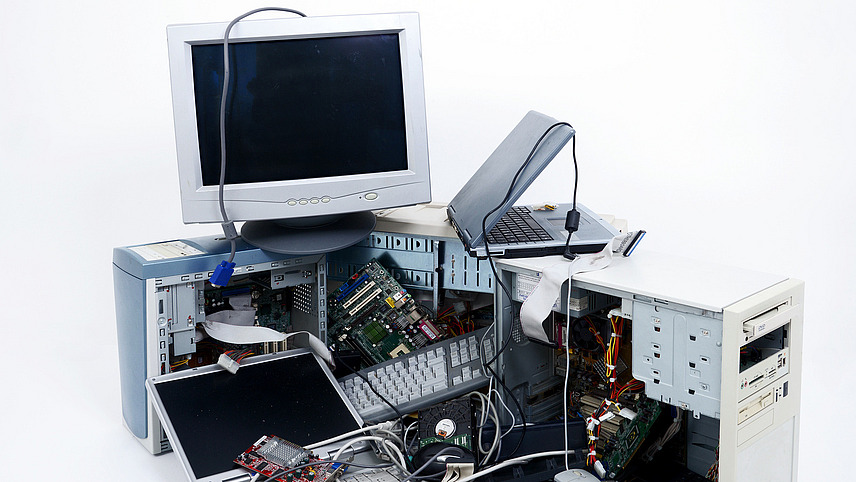 Collection of electrical appliances against a white background, including disassembled computers, monitors and laptops.