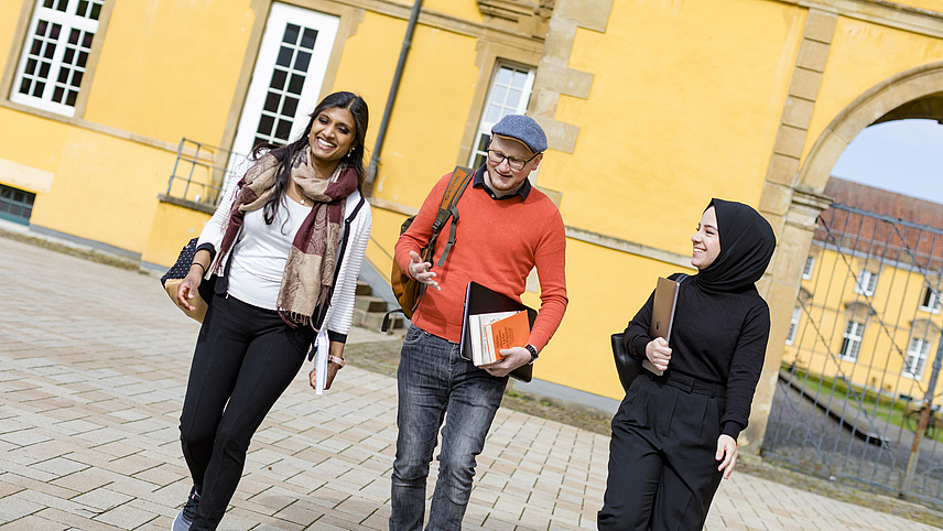 Three people are walking through the castle courtyard and talking. 