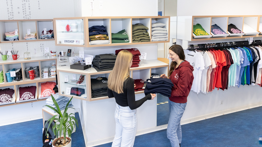 A saleswoman advises a customer on the purchase of a hoodie.