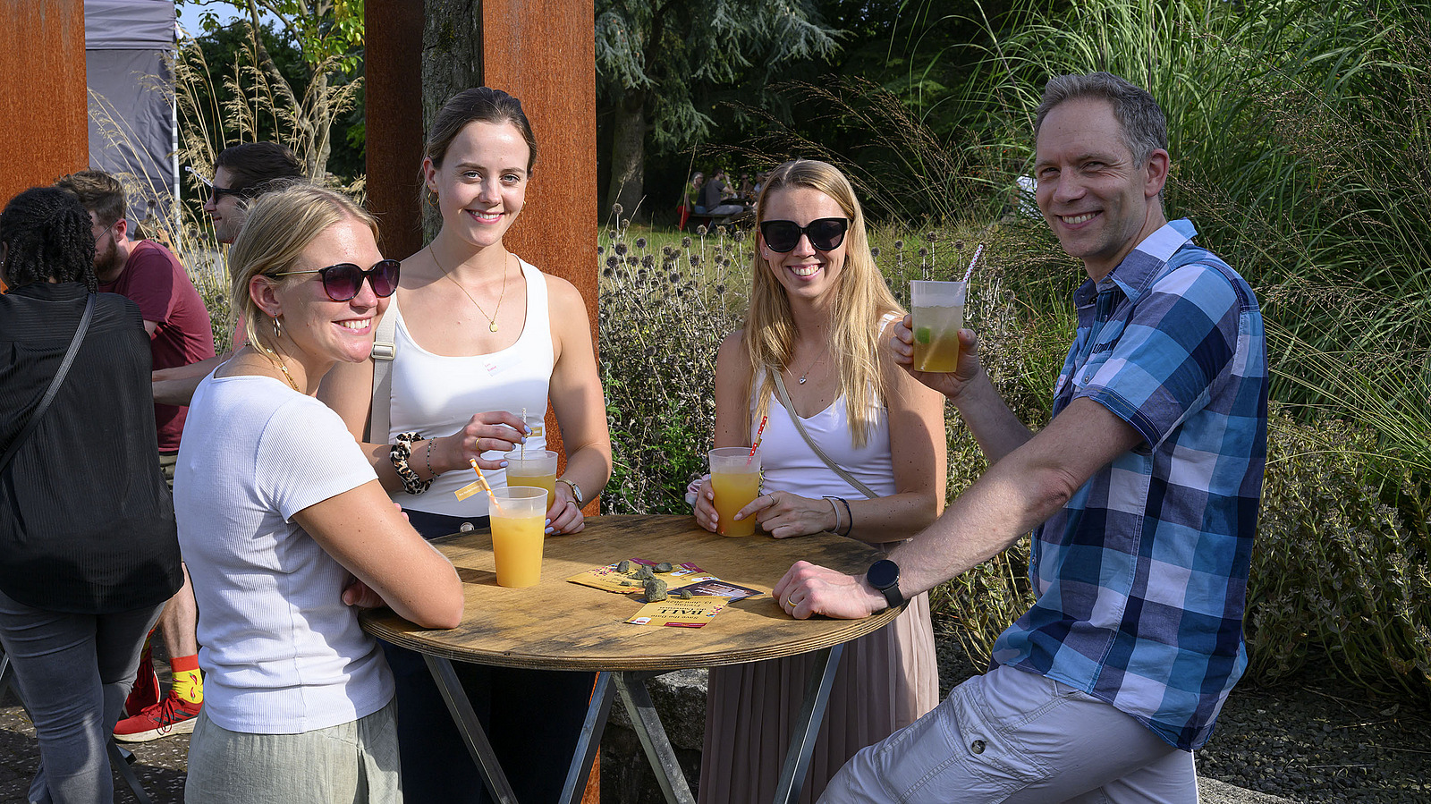 Several cheerful people with drinks at a garden party.