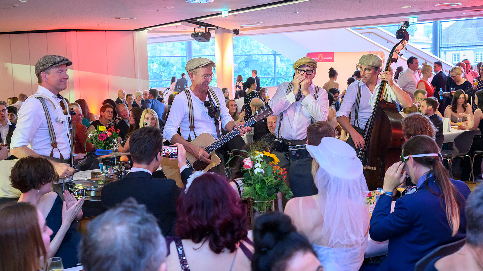 Four musicians play in the midst of standing and seated guests