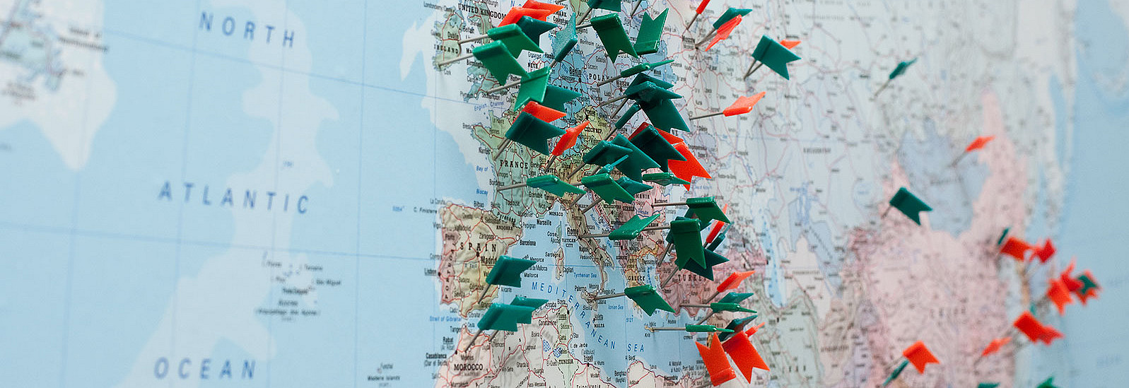 A world map with a focus on Europe with flags in red and green.