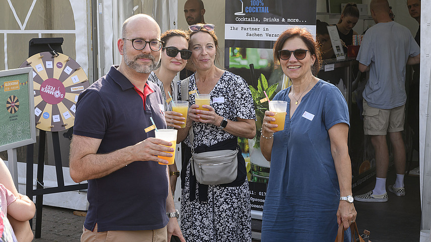 Several cheerful people with drinks at a garden party.