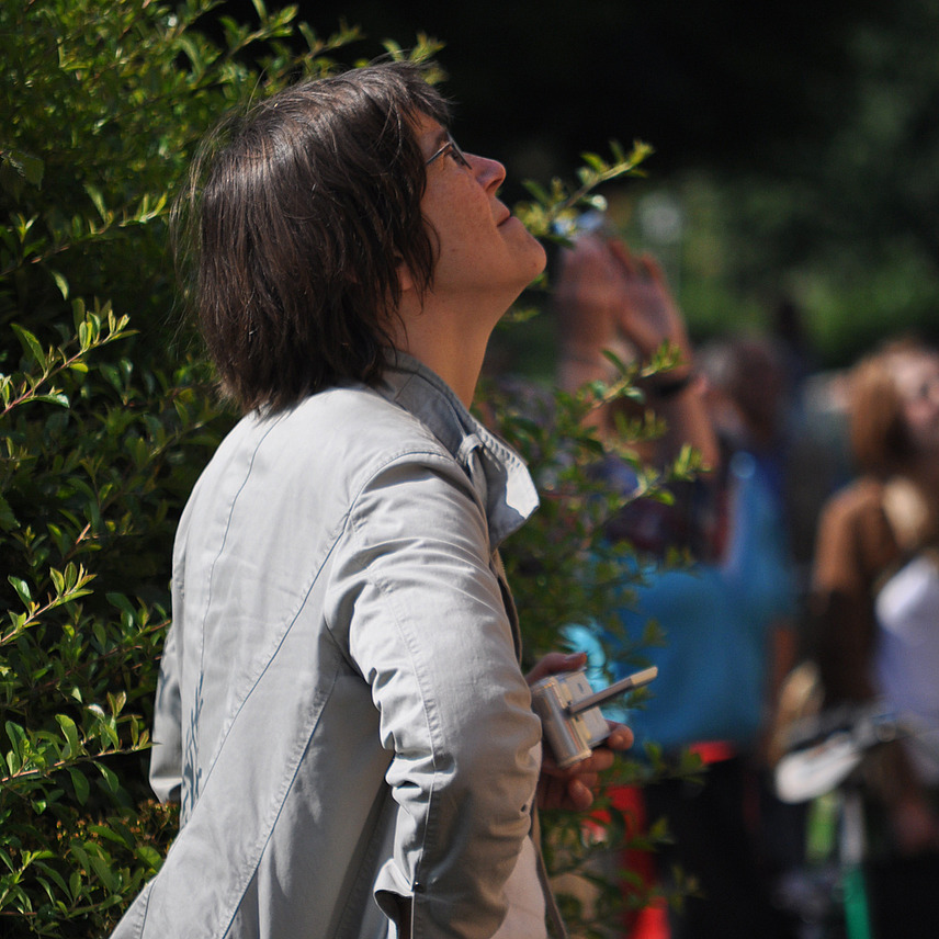 Claudia Kayser-Kadereit ist im Profil zu sehen, sie steht mit den Händen an den Hüften vor einer Hecke am Osnabrücker Schloss und schaut nach oben,