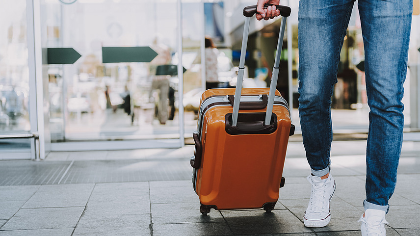 A man with a suitcase in his hand walks at an airport.