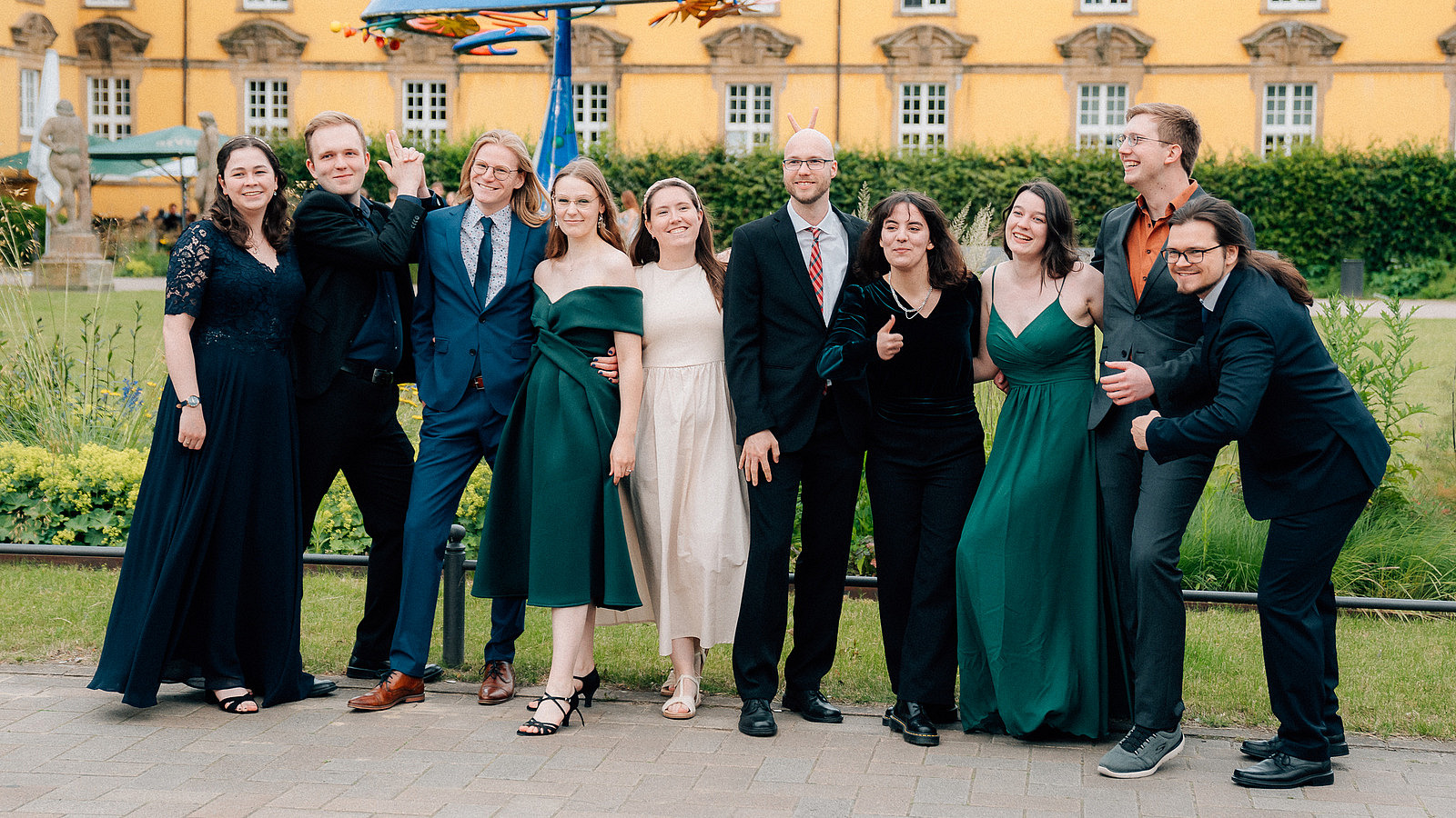 Several people stand in a good mood in front of the Osnabrückhalle