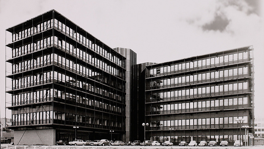 Black and white photograph of a large wing building with glass fronts