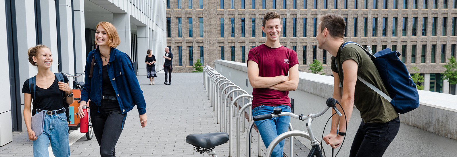 Vier Studierende bei den Fahrradständern vorm Rechenzentrum der Universität.