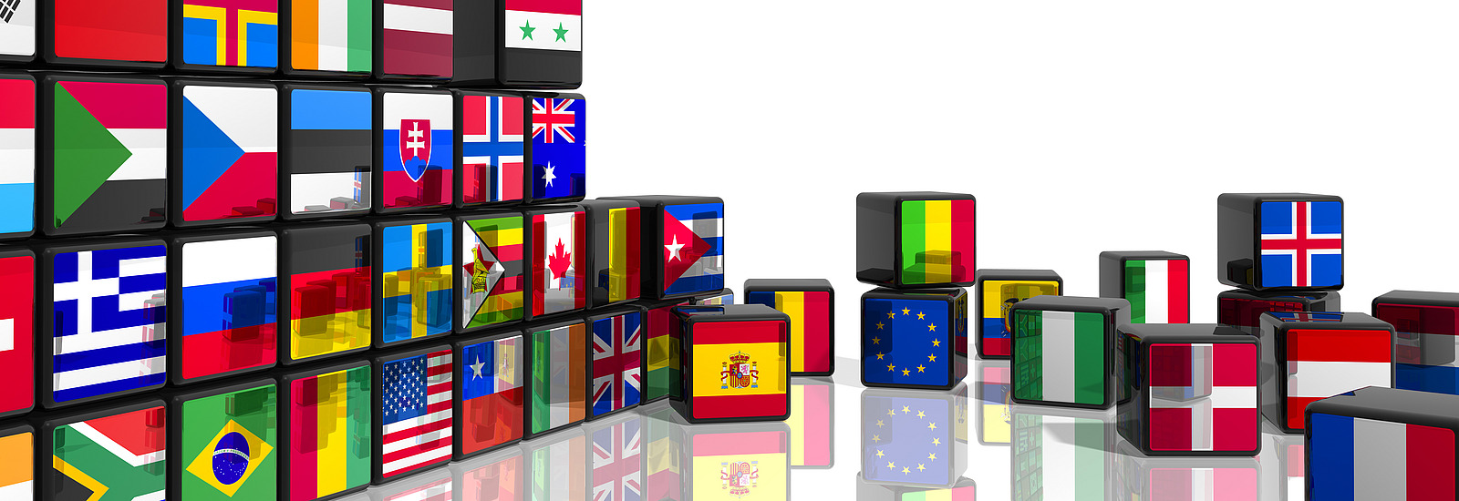 Many cubes are stacked as a wall on the left of the picture and scattered on the floor on the right. They have the flags of various countries printed on them.