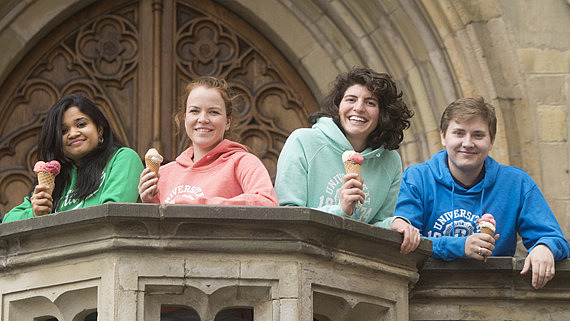 International students stand on the steps of Osnabrück Town Hall with an ice cream in their hands, dressed in colorful clothes and smiling