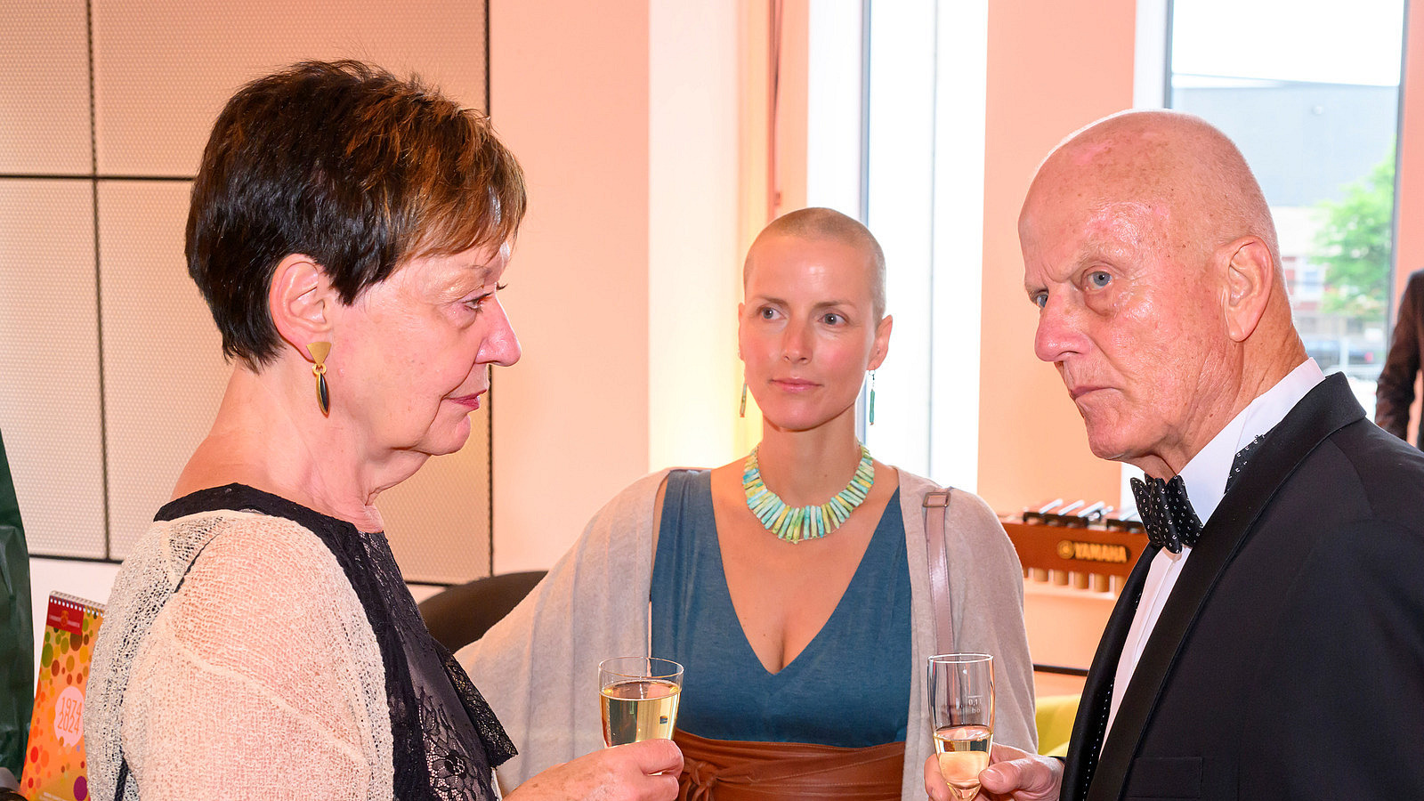 Three people stand together and talk