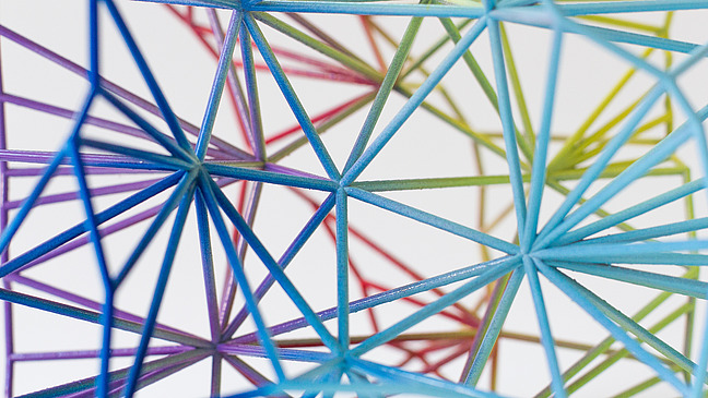 Complex structure of colorful, thin rods that are connected to each other and form a network. The rods have different colors, including blue, green, purple and red.