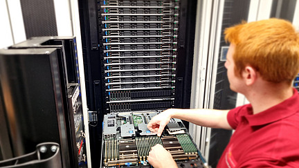 An employee checks a server in front of a server rack in the data center.