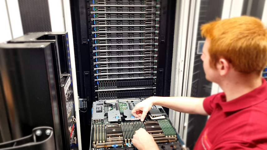 An employee checks a server in front of a server rack in the data center.