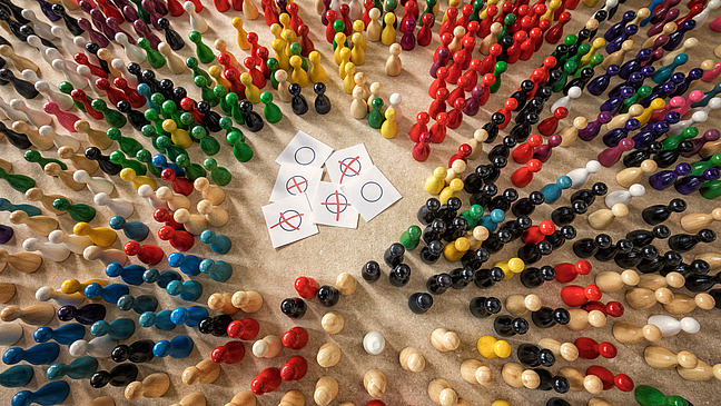 Bunte Spielsteine versammeln sich um Wahlzettel
