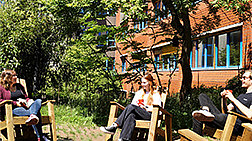 Angehörige des Fachbereichs Biologie sitzen mit Kaffeebechern auf den Holz-Deckchairs im Innenhof der Osnabrücker Biologie