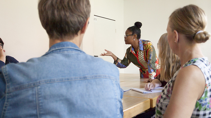 Students sit together at a table and have a discussion.