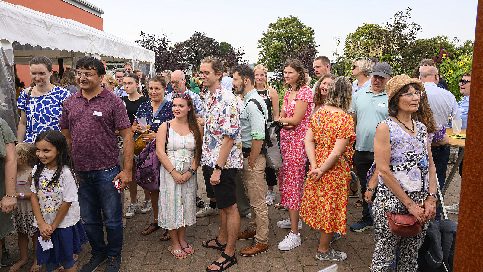 Mehrere sommerlich gekleidete Personen auf einem Fest im Freien.