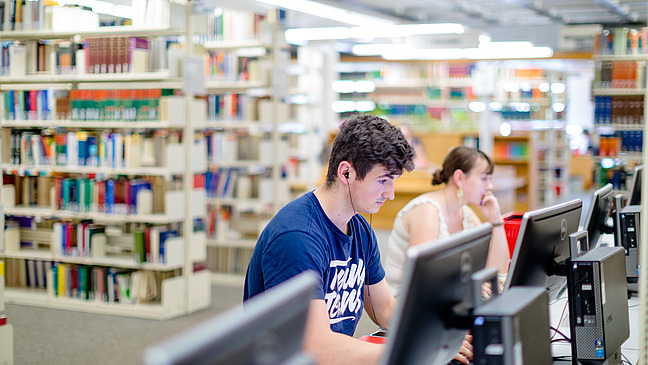 Zwei Personen sitzen an Computern in der Bibliothek Alte Münze.