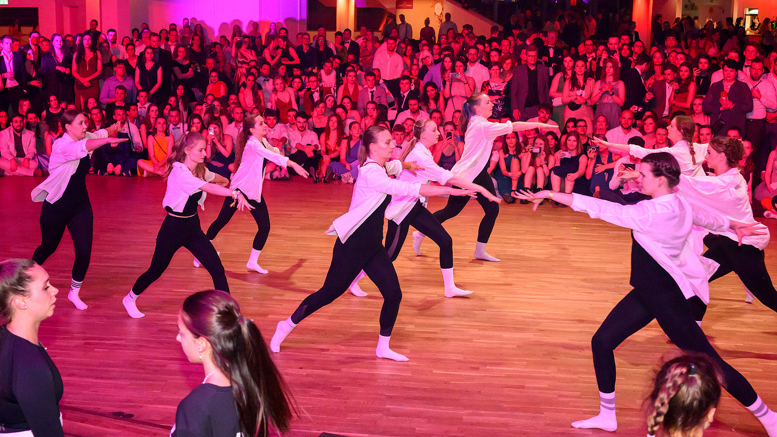 Rock'n roll formation on the dance floor, numerous people watching in the background