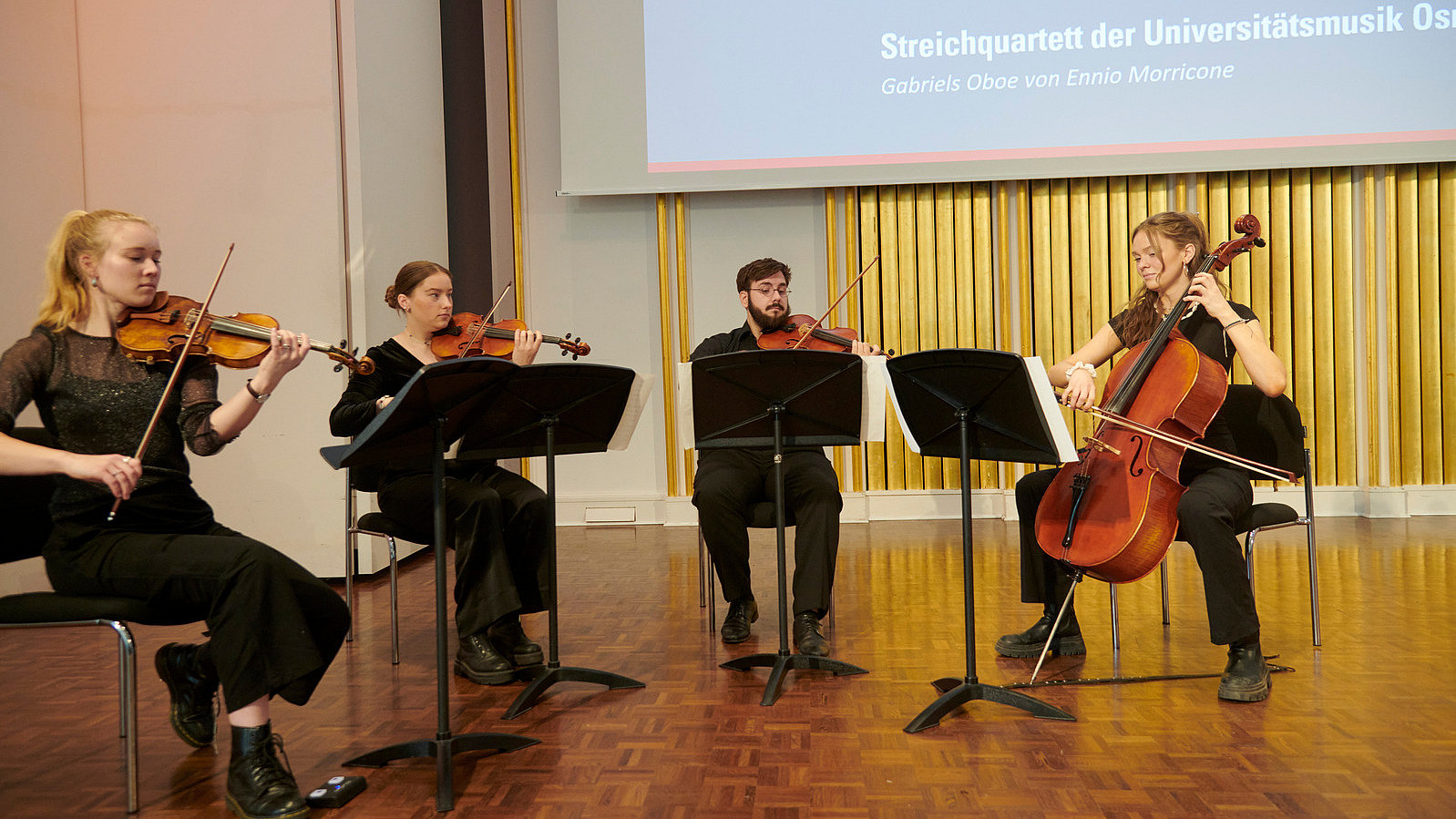 Vier Personen mit Streichinstrumenten auf einer Bühne