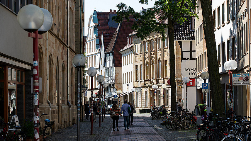 Eine Straße in Osnabrücks Altstadt. Hier stehen einige Gebäude aus Sandstein und Fachwerkhäuser.