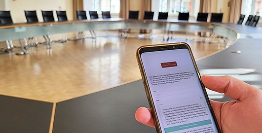 Aufnahmen des leeren Senatssitzungssaals und eines Smartphones mit der Wahl-App der Uni