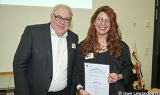 A man and a woman, the woman holding a certificate