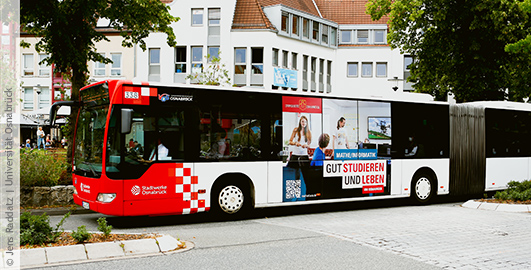 Ein Werbebild der Univerität ist an der Seite eines Busses zu sehen, die Aufschrift lautet "Mathe und Informatik. Gut studieren und leben".