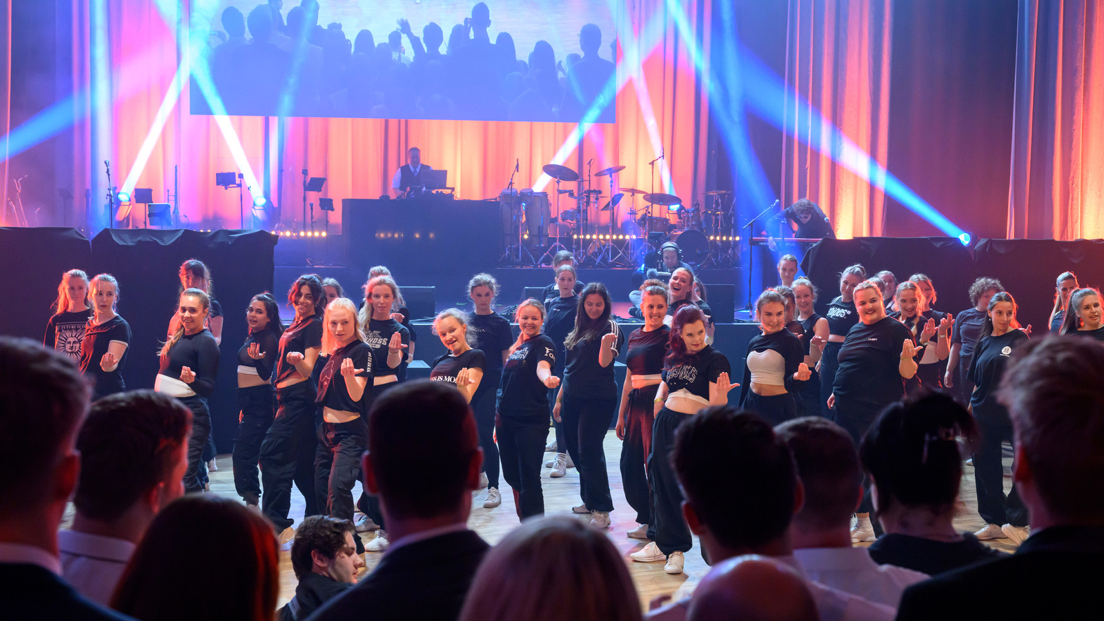 A hip hop formation on the dance floor, numerous people watching them