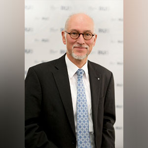 Ein Mann mit grauem Bart und Brille schaut freundlich in die Kamera